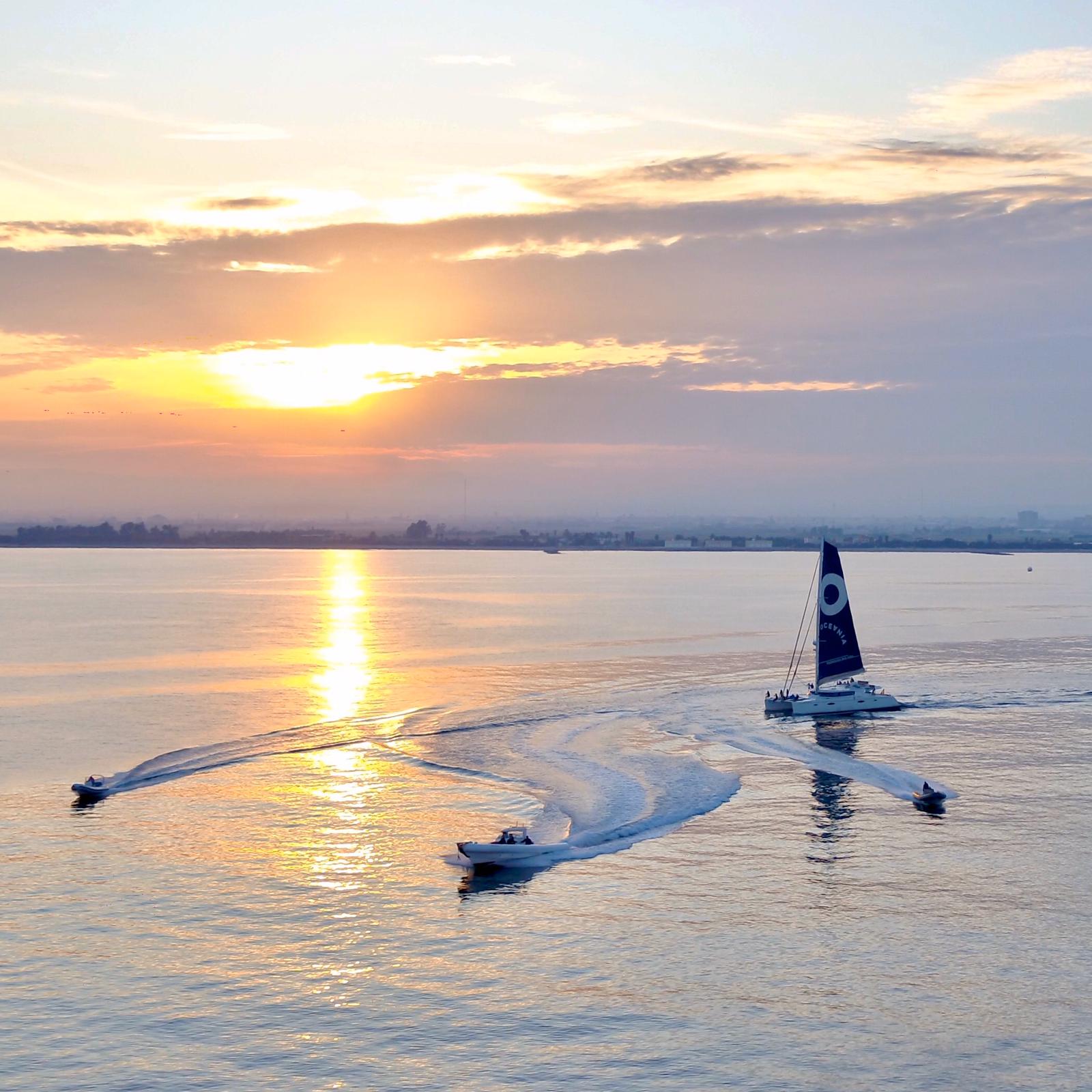 RIBs supporting a sailing vessel at sunset